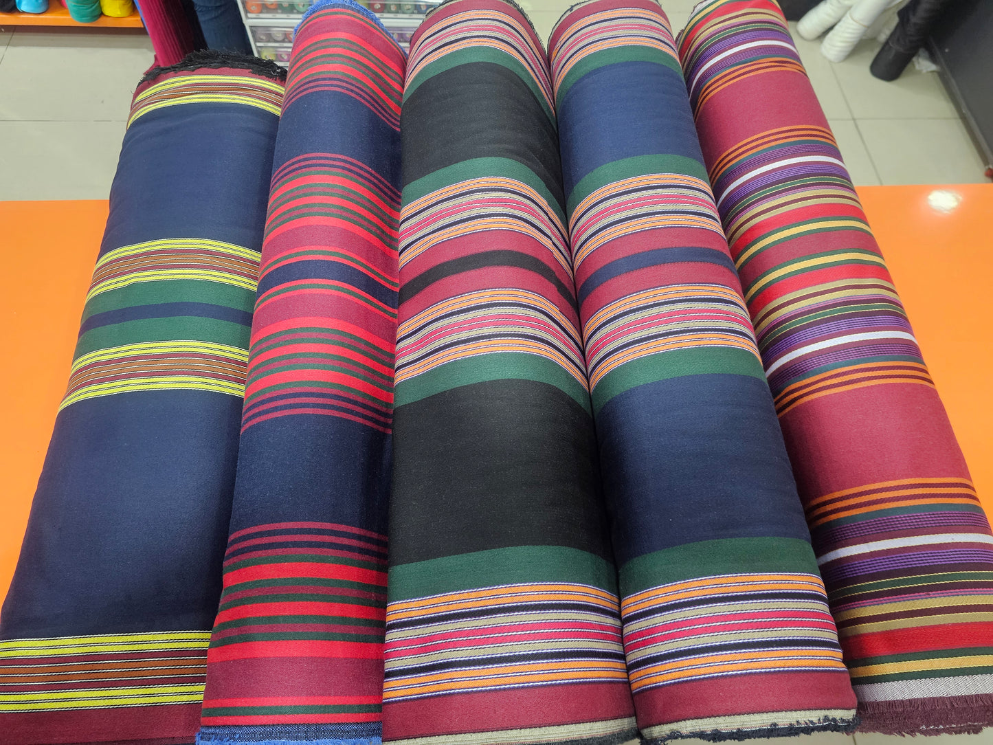 Rolls of colorful striped fabric on a flat surface
