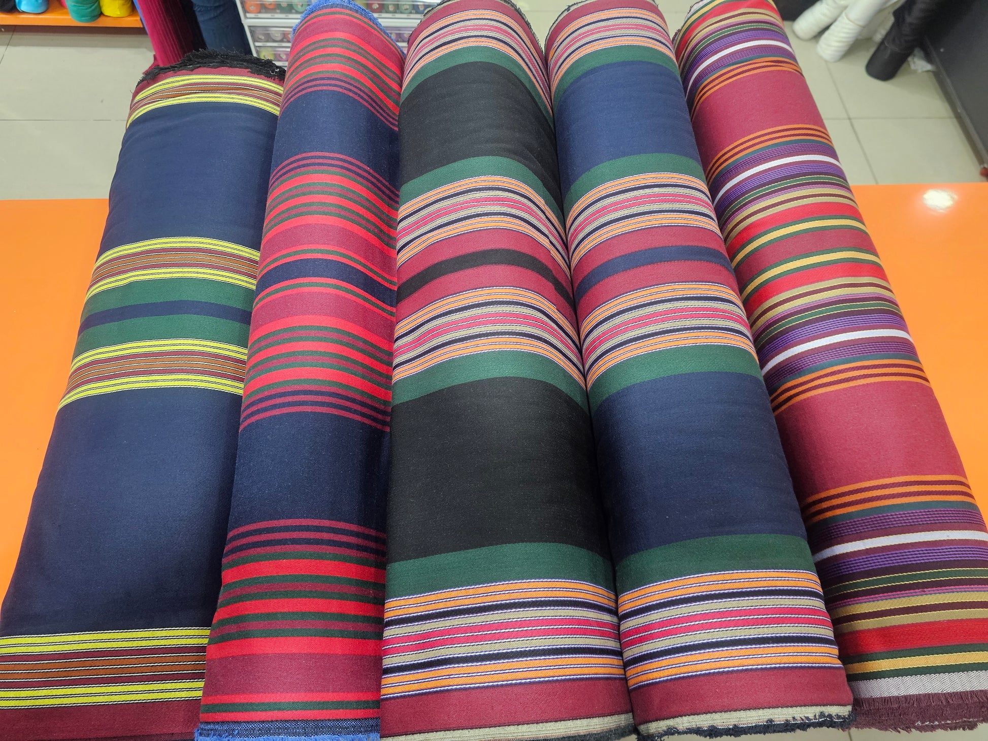 Rolls of colorful striped fabric on a flat surface